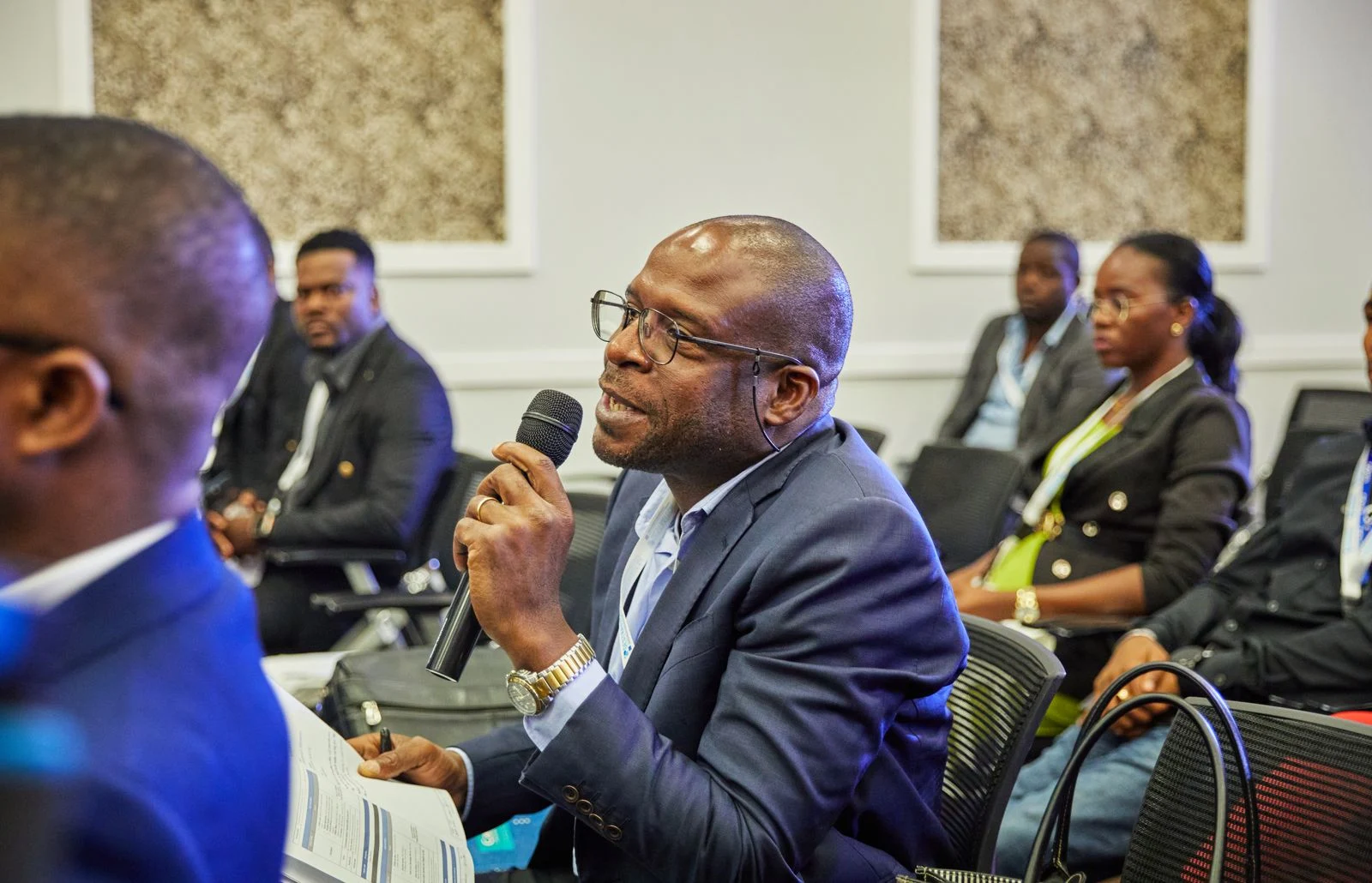 A conference participant contributing to a discussion with a microphone; illustrative stock photography